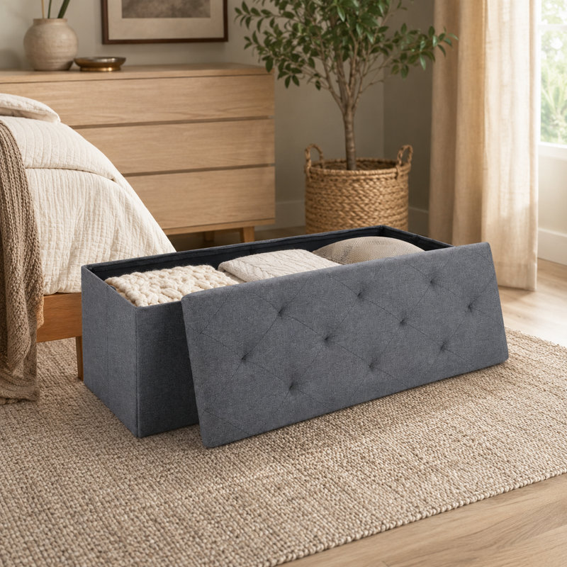 Un tabouret de rangement pliant gris de 23,25 pouces qui peut être utilisé comme tabouret de bout de lit et peut être placé dans les entrées du salon et de la chambre à coucher