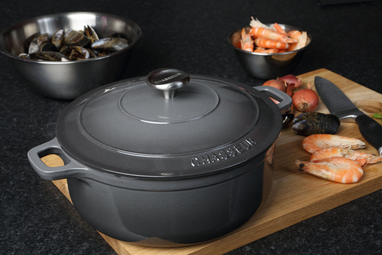 what is a dutch oven gray dutch oven on a cutting board next to seafood and a knife