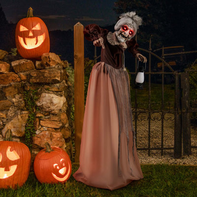 Illustration animée grandeur nature d'Halloween animée et parlante, vieille dame avec des yeux rouges et une lanterne