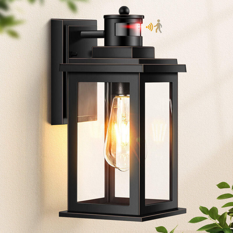 Applique murale extérieure Black Gold avec détecteur de mouvement crépusculaire, douille E26 et verre transparent.