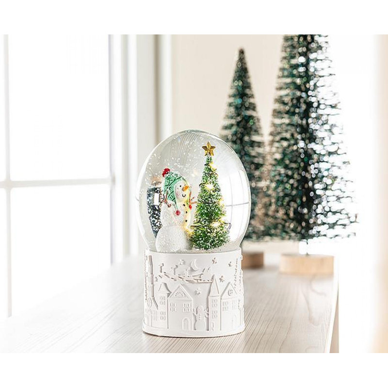 Boule à neige bonhomme de neige avec arbre à DEL sur une scène de village de base