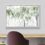 Framed landscape canvas wall art featuring a green and white watercolor forest scene hanging above a desk.