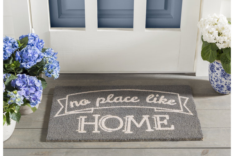 Gray doormat that says no place like home on it.