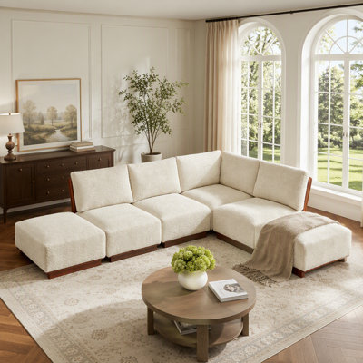 Canapé d'angle modulaire en tissu bouclé avec pouf offrant des configurations d'assise flexibles et un confort ergonomique pour les espaces de vie.