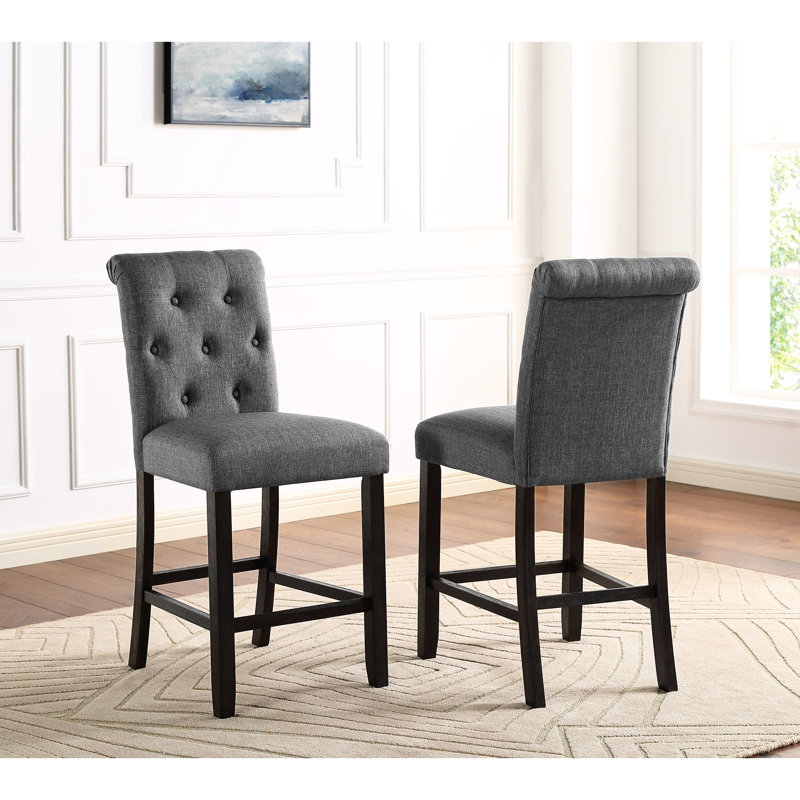 2 pièces tabouret de comptoir gris. Bois massif avec sièges et dossiers élégants. Rembourré pour un confort maximal. Pieds en bois au fini foncé. Chaises à haut dossier délicatement courbées. L 23 po x P 19 po et H 40,92 po. Siège: l 19 po