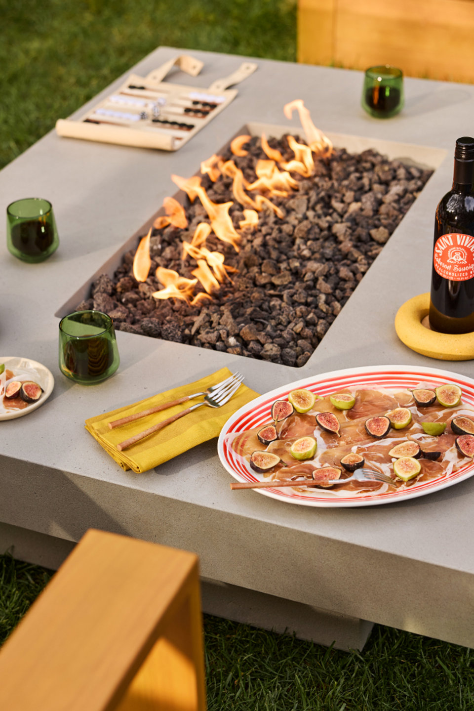 Grey fire pit table with wine and appetizer plates.