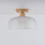 Plafonnier à une lumière avec grille en verre, fini texturé bois et abat-jour en verre transparent.