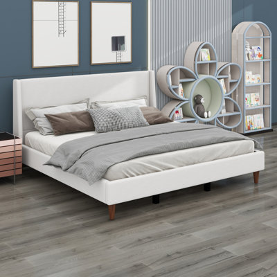 Lit plateforme tapissier avec tête de lit à oreilles et pieds en bois
