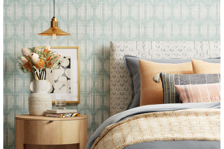 modern boho bedroom with green abstract wallpaper behind an upholstered headboard and round nightstand