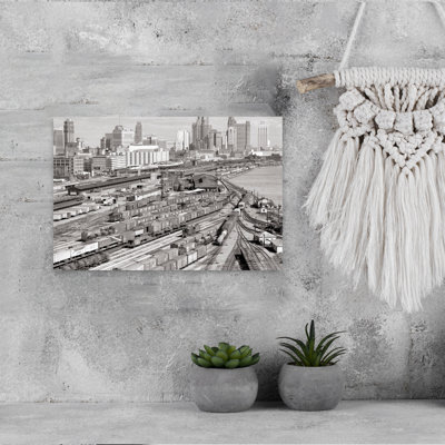 1960s INDUSTRIAL FREIGHT TRUCKING AND RAILROAD BOXCAR TRAIN YARDS ALONG RIVER CITY BUILDINGS SKYLINE IN B G DETROIT MICHIGAN USA by H. Armstrong Roberts - Wrapped Canvas Print