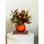 Astilbe et arrangement de grenade d'automne dans un vase de citrouille en verre