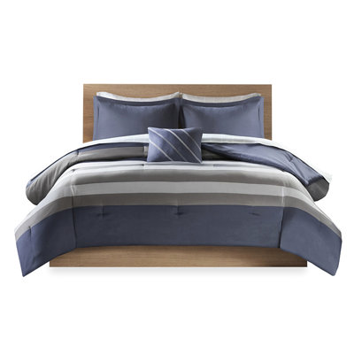 Lit avec édredon rayé bleu et gris et drap avec oreiller décoratif