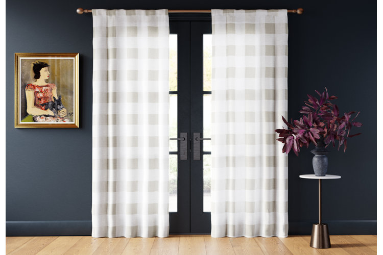 Room with French doors partially covered on each side by white and gray plaid curtains and next to a framed wall painting.