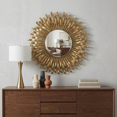 Magnifique miroir mural au fini doré et au design complexe, ajoutant une touche de glamour à tout espace
