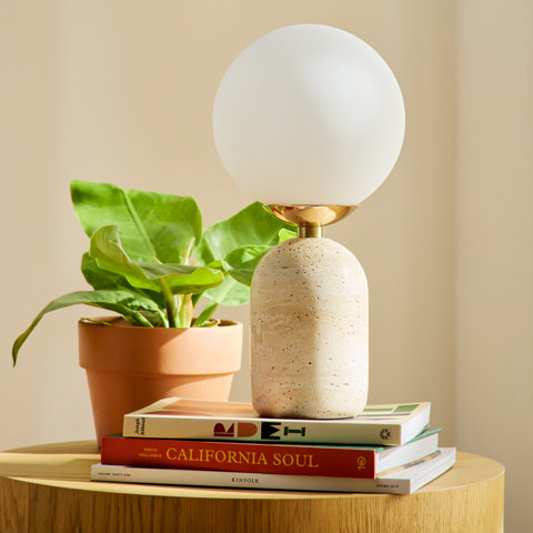 Lamp with a round white shade on books, including California Soul