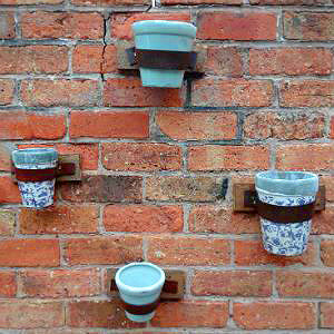 Pots affixed to brick wall with belts