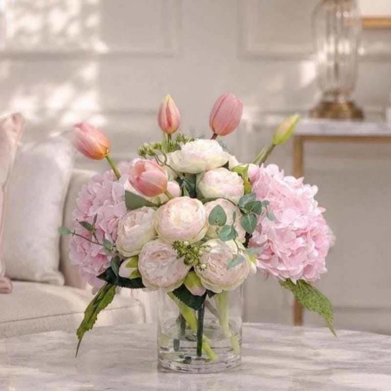Centre de table de 35,5 cm (14 po) avec hortensias, tulipes et pivoines roses au toucher réaliste, présenté dans un vase en verre.