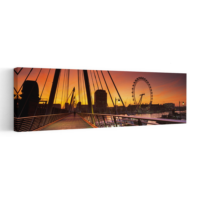 Bridge Across A River With A Ferris Wheel In The Background Golden Jubilee Bridge Thames River Millennium Wheel City Of Westminster London England by Mark Denton - Wrapped Canvas Panoramic Print