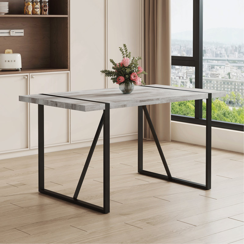 Une table de salle à manger rectangulaire rétro minimaliste avec un dessus spécialement texturé et des pieds en métal noir. Plateau de table contemporain en panneau de fibres à densité moyenne gris minimaliste.