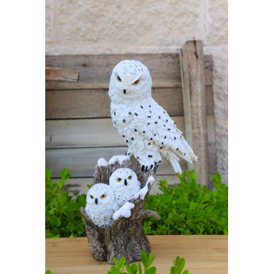 Figurine familiale représentant une chouette harfang des neiges et ses deux petits sur une souche d'arbre enneigée