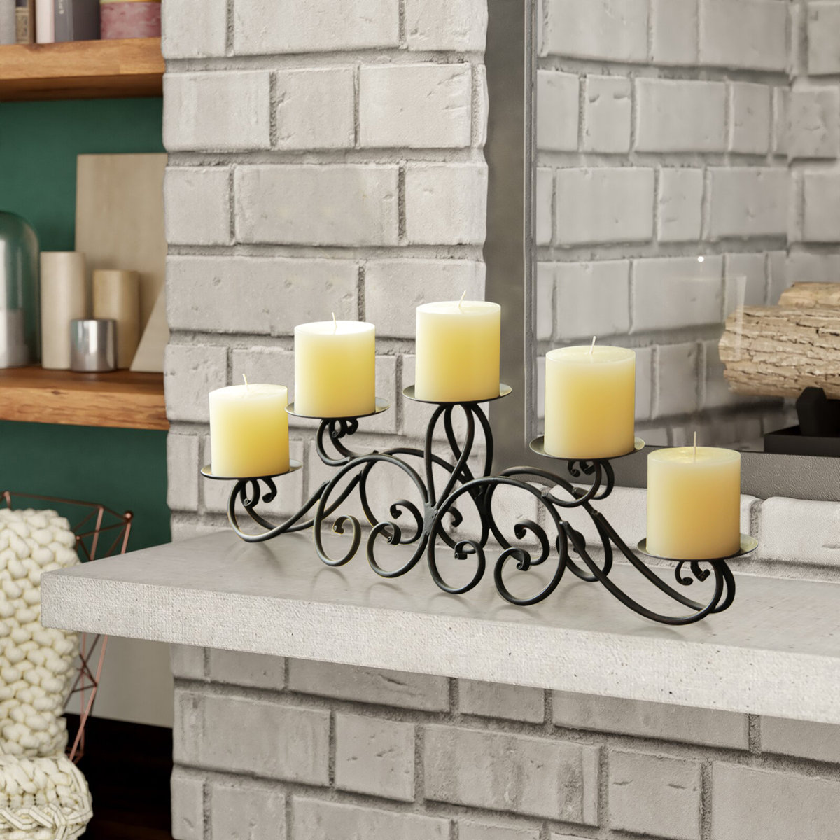 Wrought iron candle holder with five ivory pillar candles displayed on a white brick mantel in front of a mirror