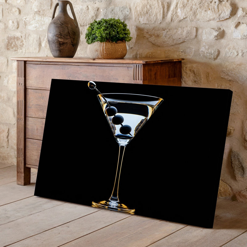 Toile d'un élégant verre à martini élégant rempli de liquide cristal transparent présentant trois olives sombres en brochette sur une toile argentée