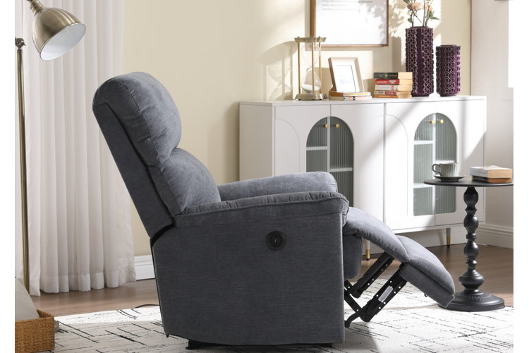 A gray recliner in the reclined position beside a gold floor lamp, a black pedestal side table, and a white sideboard.