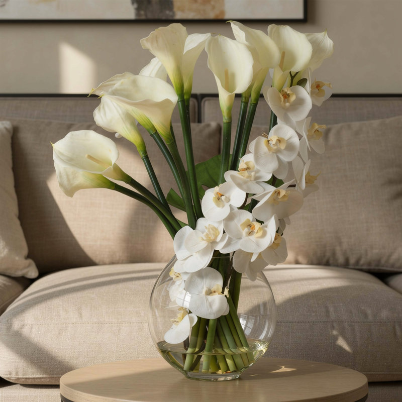 Orchids, Calla Lily And Philodendron Leaves Arranged In A Clear Circular Glass Vase