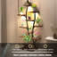 Support pour plantes d'intérieur en forme de vase avec lampes de croissance et tablette métallique.