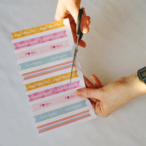 birds-eye view of hands cutting out mini cupcake flags from paper