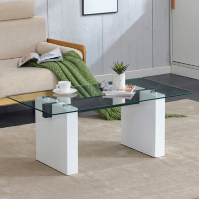 Table basse moderne en verre trempé transparent minimaliste, jumelée à des colonnes décoratives en panneau de fibres à densité moyenne blanches. Bureau d'ordinateur. Table de jeu