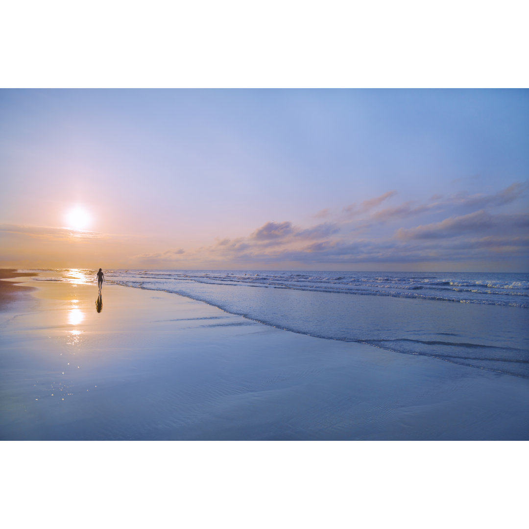 Mann geht am Strand bei Sonnenaufgang by FangXiaNuo - Leinwandbild