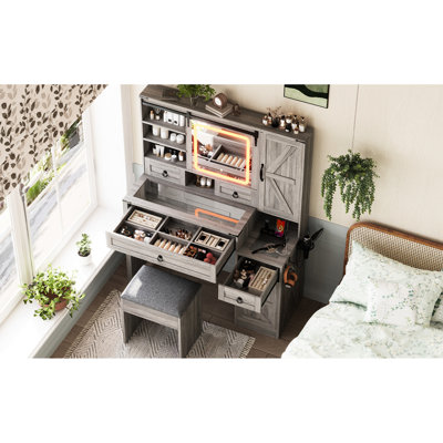 Bureau de coiffeuse avec miroir coulissant, lumières, plateau en verre et station de charge. Dans 4 tiroirs gris, 2 armoires et un tabouret pour une routine de maquillage confortable