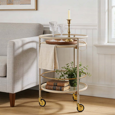 Chariot-bar rond avec tablettes en verre trempé et accents dorés, finition blanche vieillie, idéal pour les décors modernes et rétro