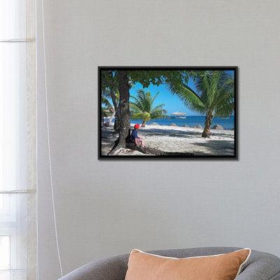 Touriste se reposant sous des palmiers sur la plage à Palmetto Bay, Roatan Island, Honduras par Tim Fitzharris - reproduction de photo sur toile tendue