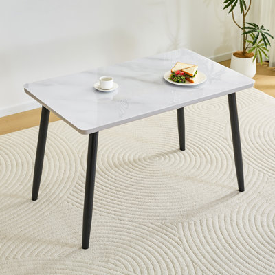 Table de salle à manger moderne et minimaliste, pour 4 à 6 personnes. Comptoir en verre trempé + panneau de fibres à densité moyenne inférieur, texture imitation marbre, pieds fuselés en métal noir. Convient aux restaurants minimalistes.