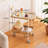 2-Tier Indoor/Outdoor Rolling Bar Cart with Tempered Glass Top, PVC Wicker Detail, Bamboo Lower Tray and White Steel Frame