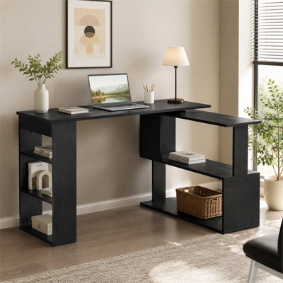 Black 360-degree rotating L-shaped home office desk with storage shelves; features a flexible, adjustable layout.