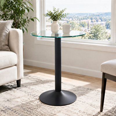 Table d'appoint ronde moderne avec plateau en verre trempé transparent, bords polis et pied en métal noir mat. Dimensions : base lestée de 40 cm de large, 50 cm de diamètre, 60 cm de hauteur. Quincaillerie et instructions d'assemblage étape par étape incluses.