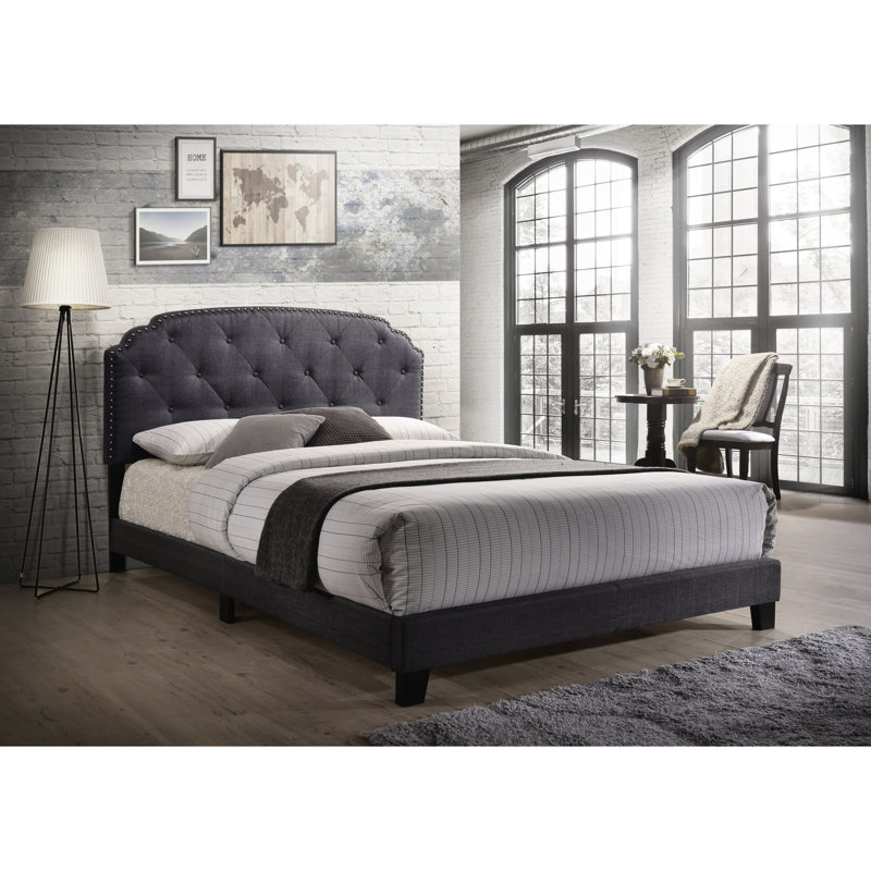 Grand lit en tissu gris avec tête de lit capitonnée et pieds élégants