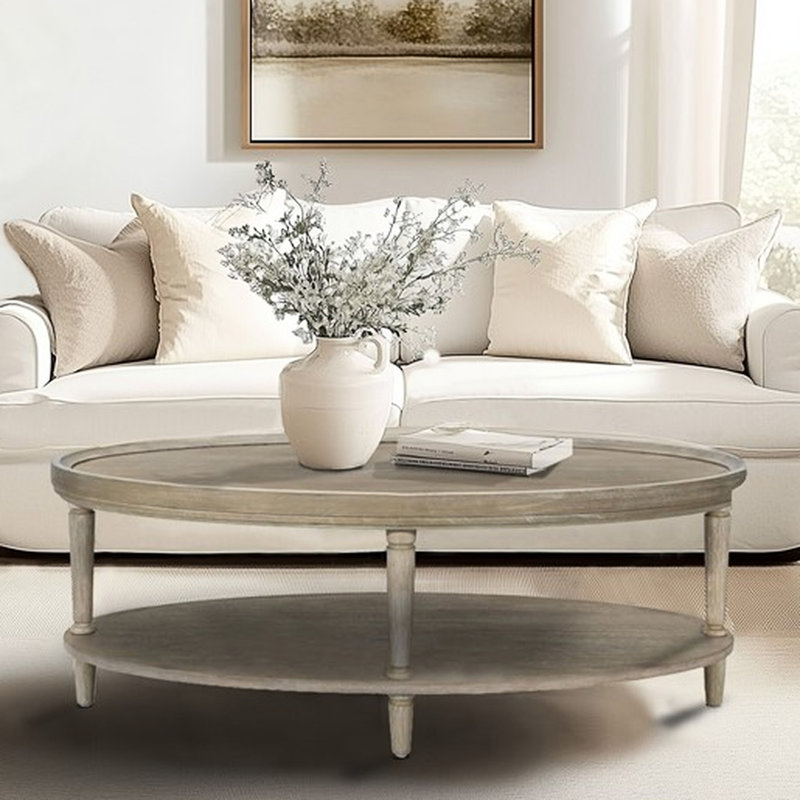 Table basse ovale avec étagères, charme classique, teinte grège recyclée, plateau en placage de bois, pattes réglables pour une élégance équilibrée.