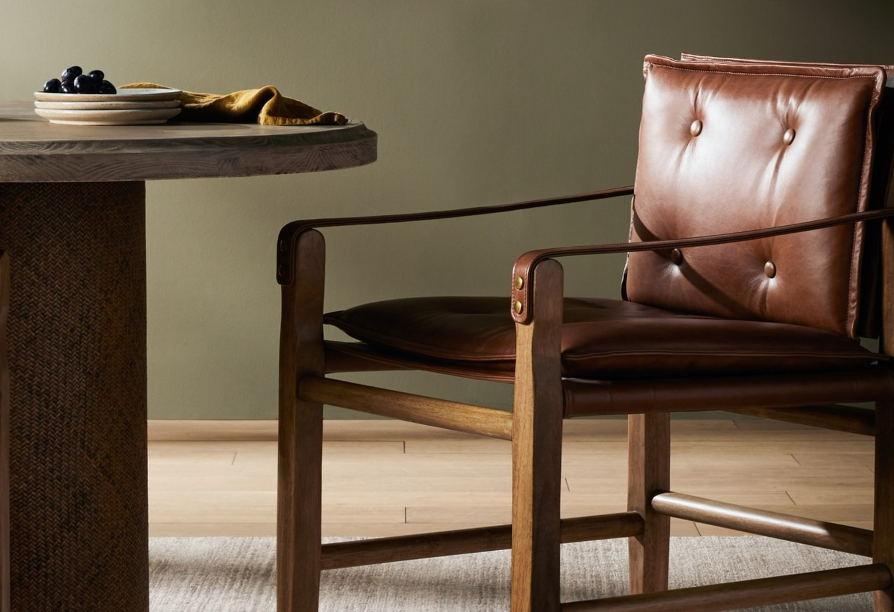 Close-up of a round wood table and a brown leather chair.