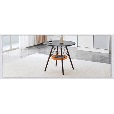Table ronde de salle à manger avec panier de rangement tressé et pieds en bois massif pour les petits espaces.
