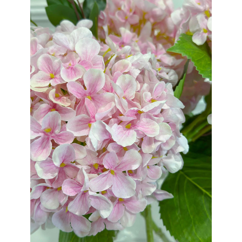 Arrangement floral d'hortensia en soie rose dans un vase cylindrique en verre transparent