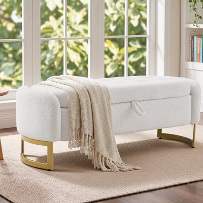 Banc de rangement capitonné Teddy avec pieds en fer courbés, structure en bois massif et plateau relevable à languette.