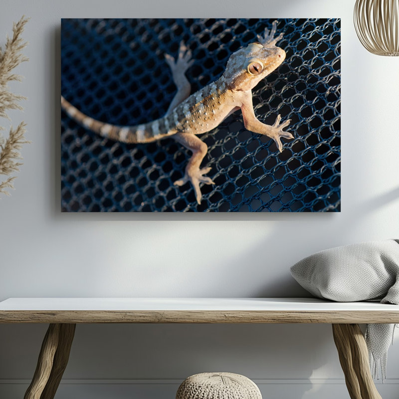 Toile, vue de près d'un gecko de couleur claire reposant sur une surface texturée en filet bleu foncé mettant en valeur sa douceur