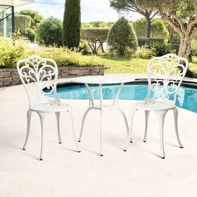 Bistro de terrasse en aluminium moulé blanc, fini rouille, orné de délicats motifs floraux. S'adapte à différents espaces et est facile à monter. Parfait pour une terrasse, un balcon, une véranda, un jardin ou une cour.