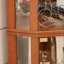 Vitrine d'angle lumineuse avec tablettes réglables en verre et dossier en miroir, idéale pour exposer des antiquités, du vin et plus encore dans les salons