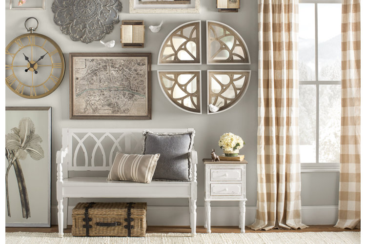 neutral colored entryway with an off-white woven area rug, white bench, beige plaid curtains, and brown and gray wall art