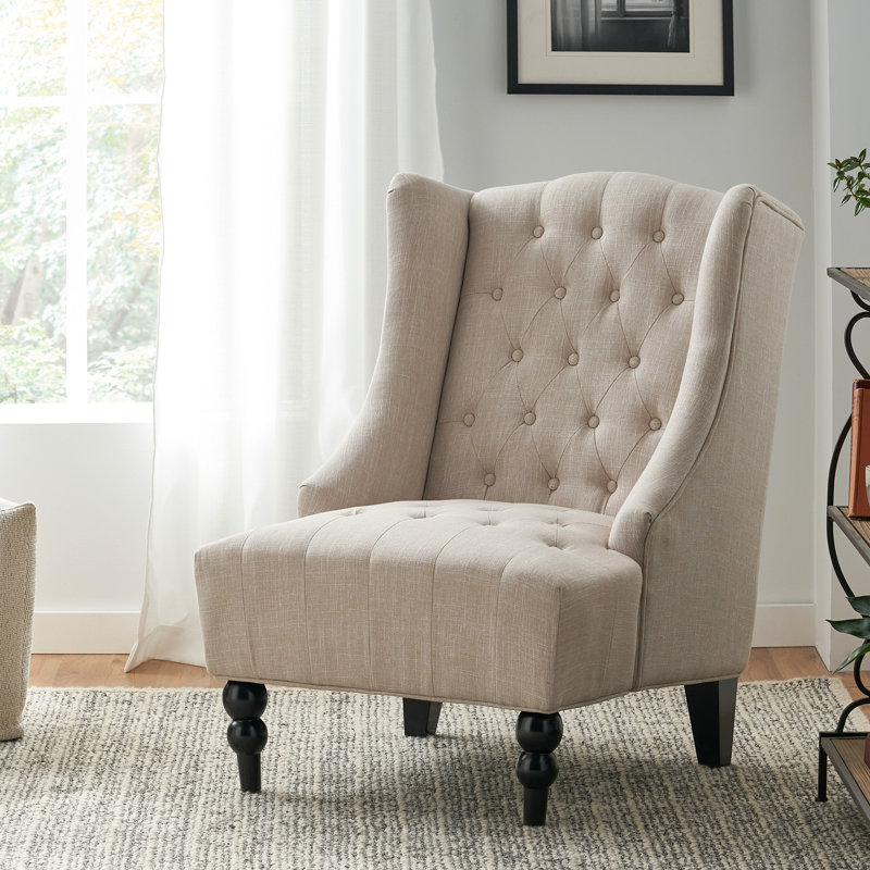 Fauteuil à oreilles beige avec capitonnage à boutons et structure en bois de bouleau robuste et élégante
